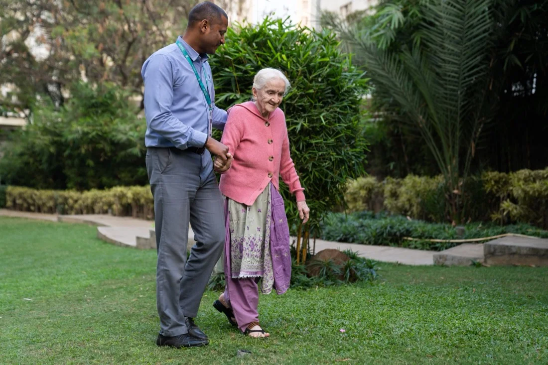A care professional accompanying an older woman outdoors