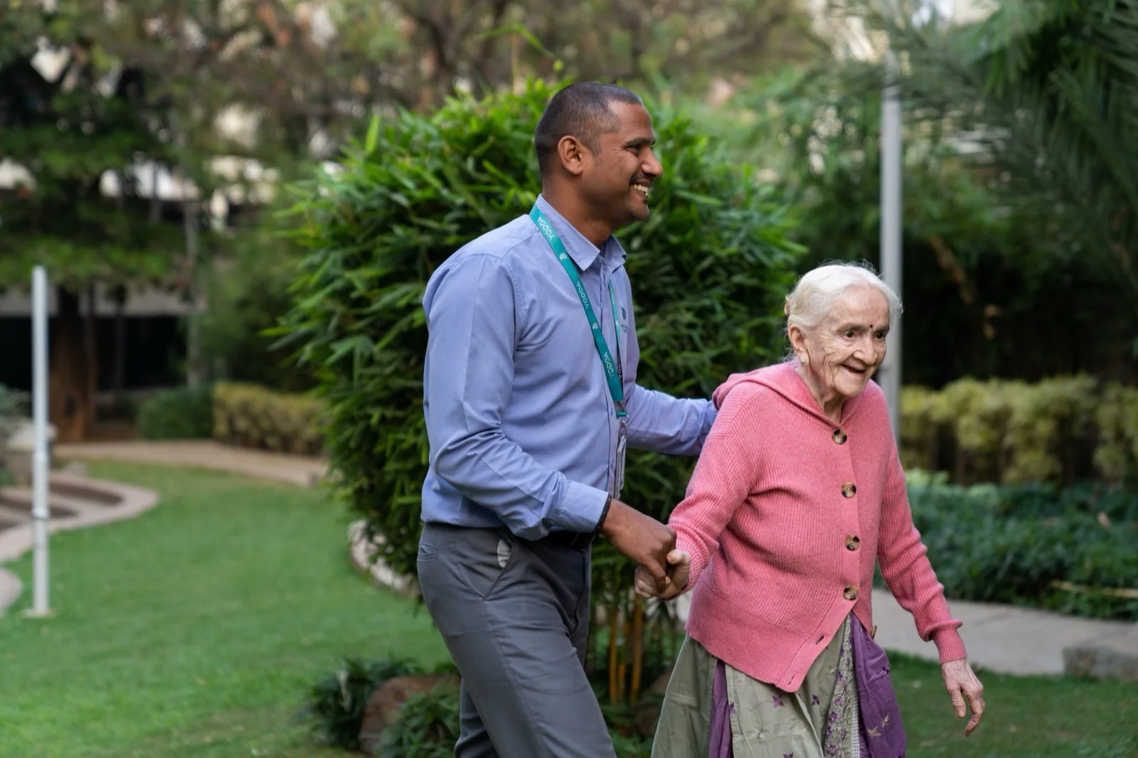 An older woman walking outdoors with a care professional